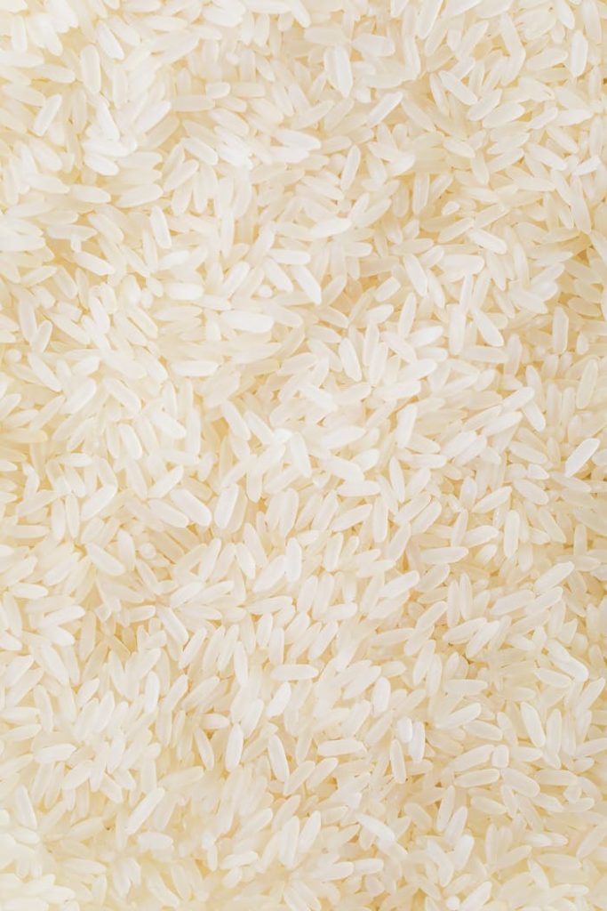 Close-up image of numerous white rice grains, showcasing texture and abundance.